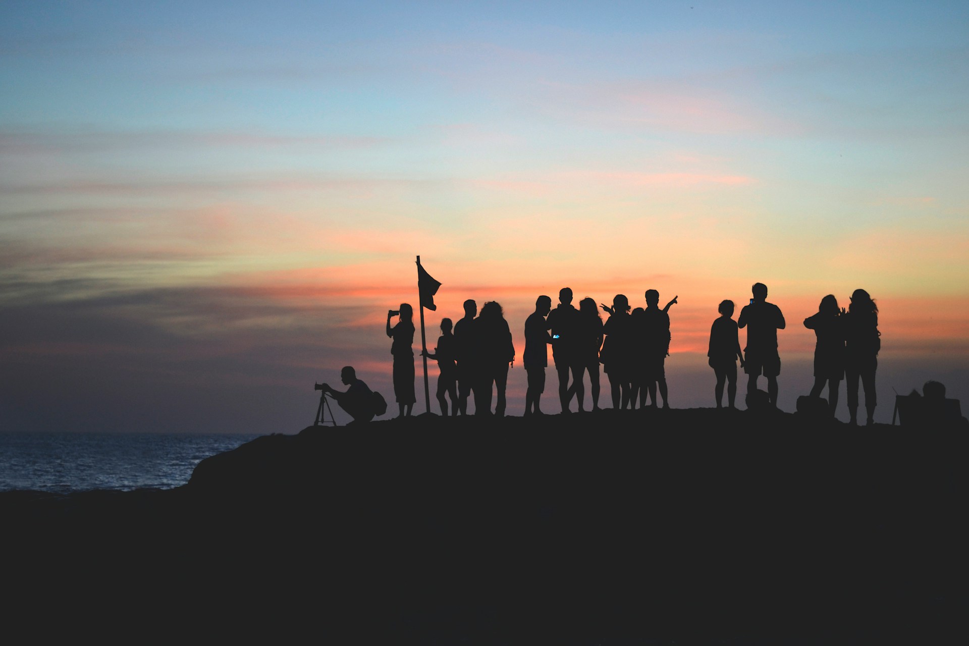 people on a cliff with sunset